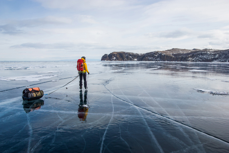 Dekorativ bild. Person på is med dragväska i skärgårdsmiljö. D